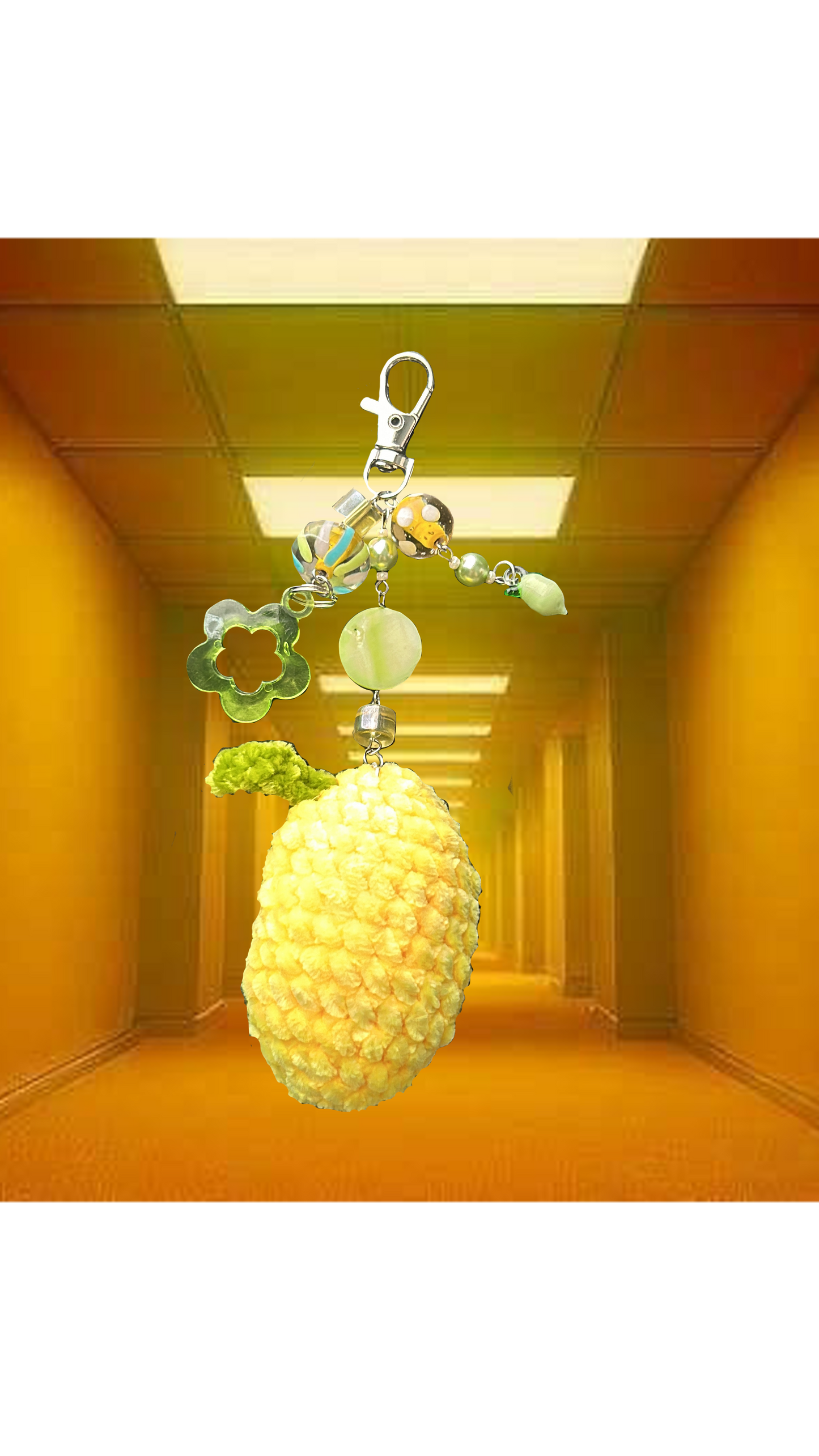 A lemon-shaped keychain with a few embellishments, placed against an orange-hued background.