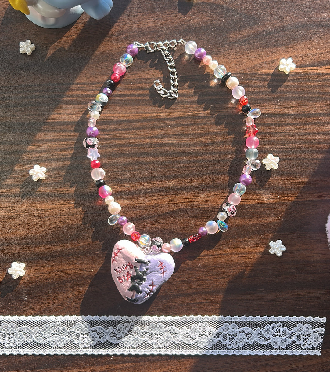 Beaded necklace with a heart-shaped pendant on a wooden surface