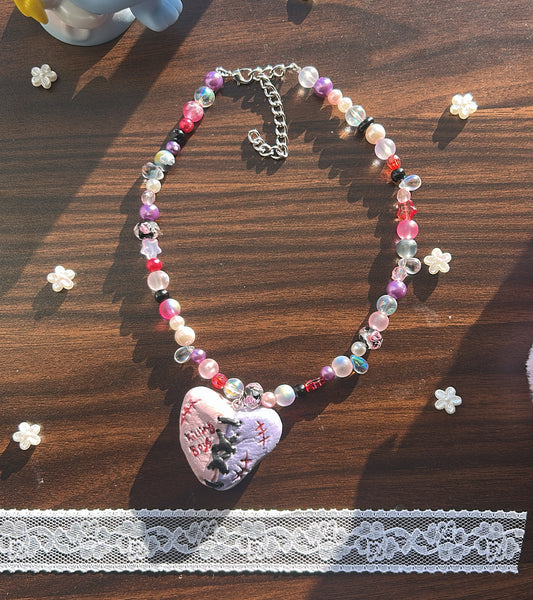 Beaded necklace with a heart-shaped pendant on a wooden surface