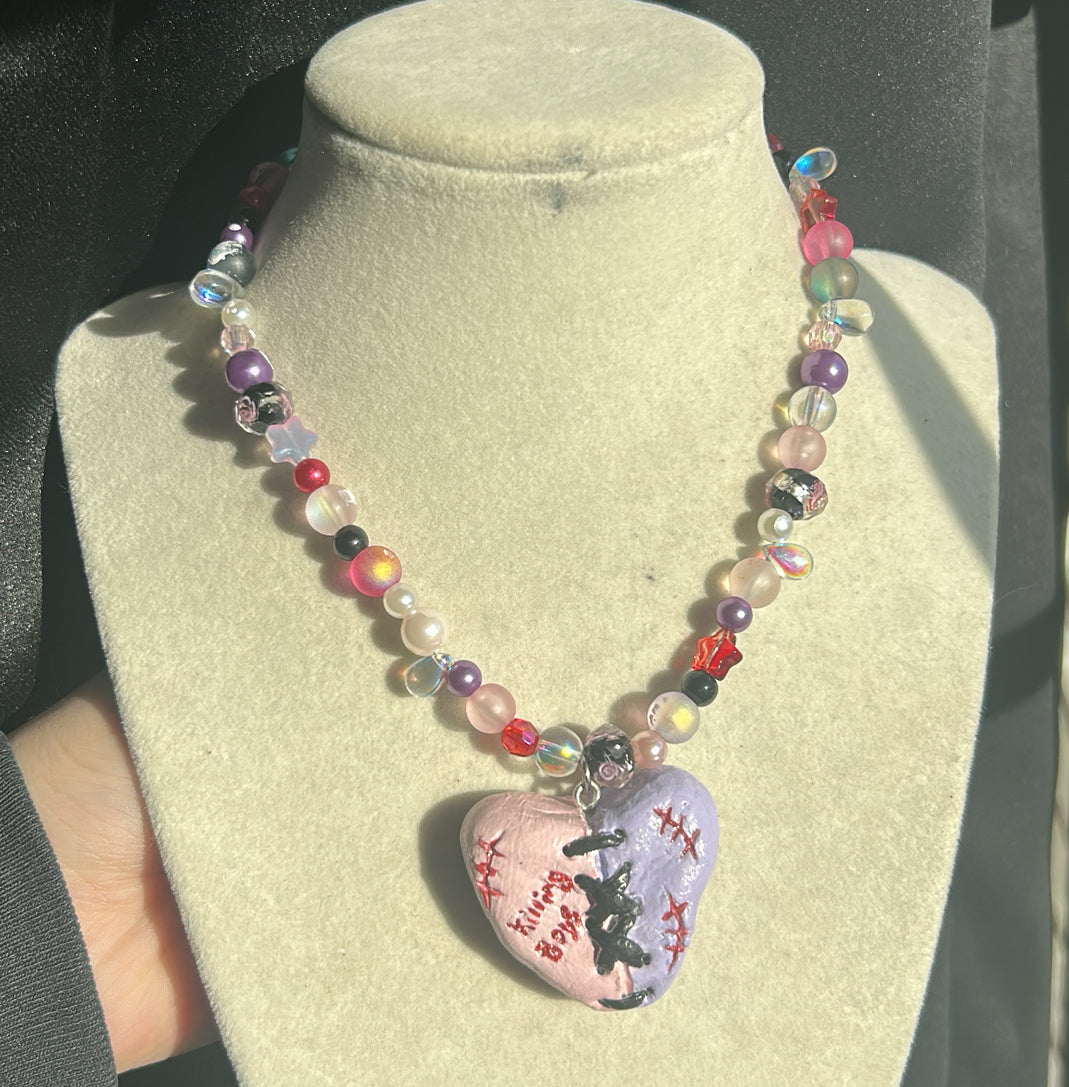 Colorful beaded necklace with a heart-shaped pendant on a mannequin bust.