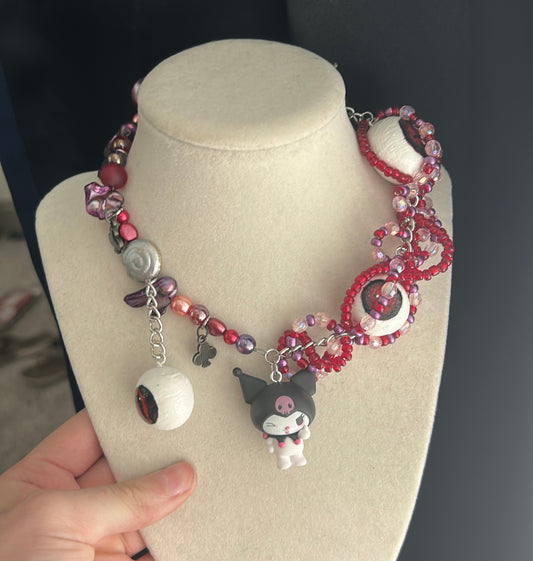Beaded necklace with a cat charm on a mannequin bust.